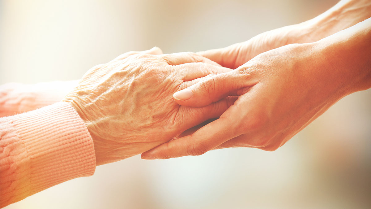 Women holding elderly hands