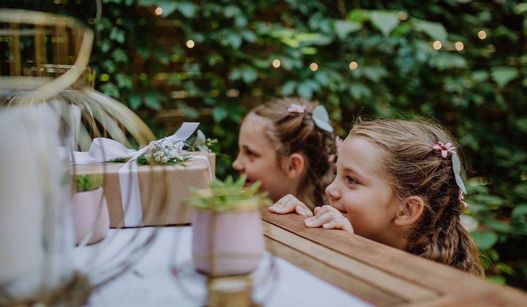 Two little girls at a wedding by table with present.